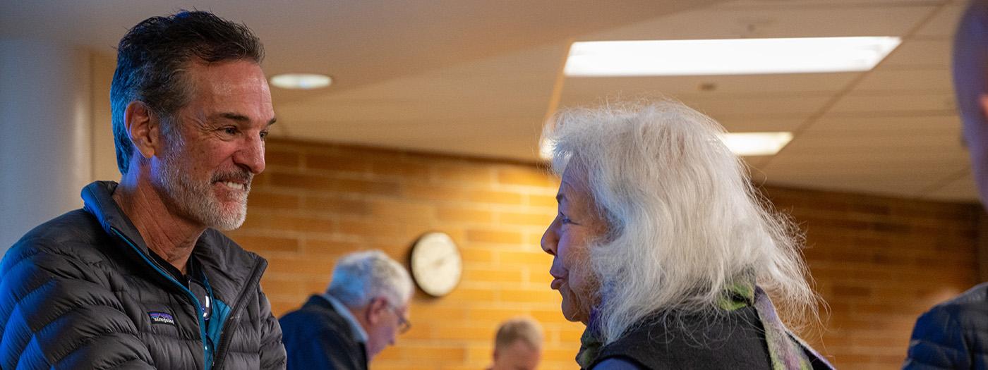 Tom Mueller smiles as he listens to a woman after his presentation.